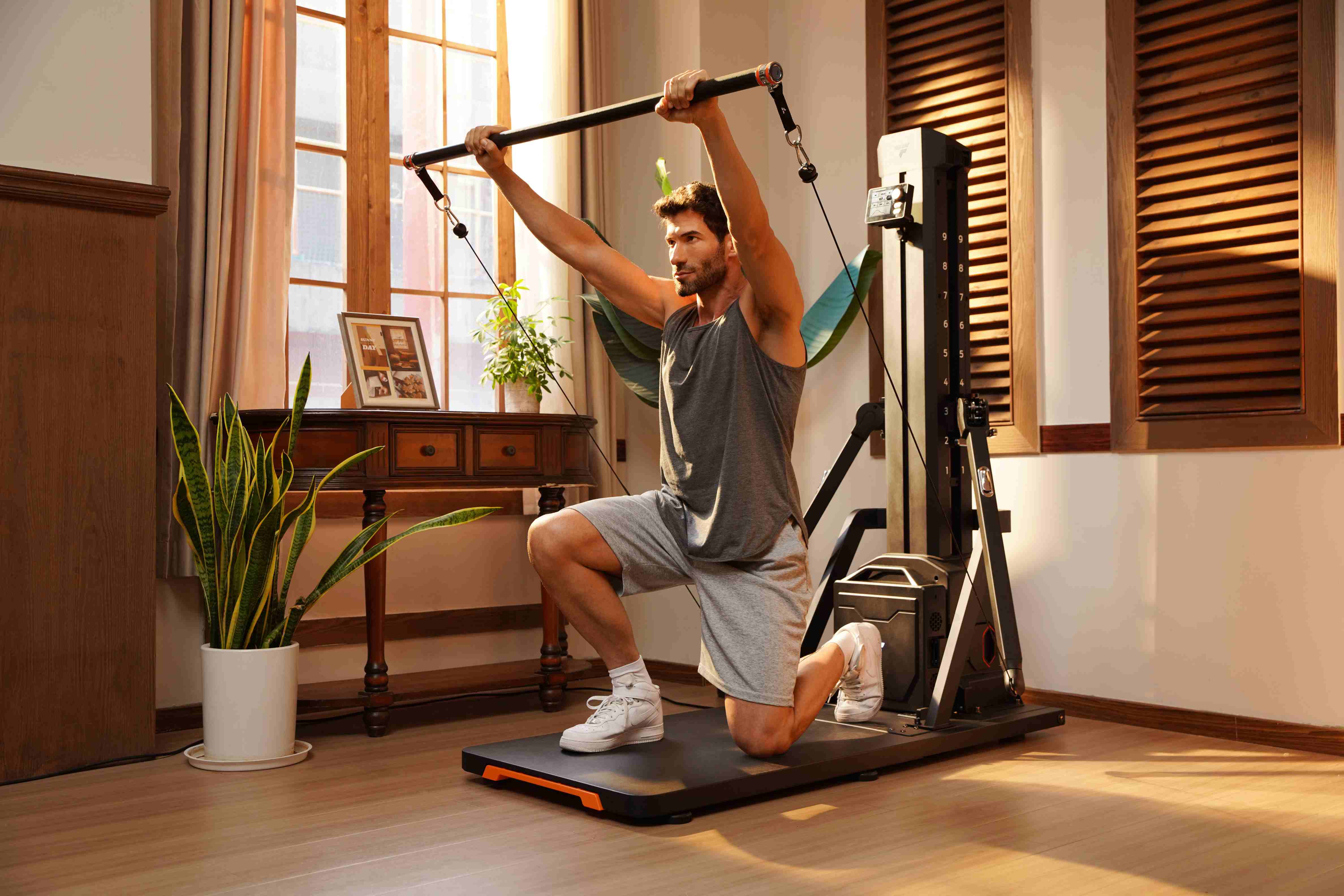 A man performing a kneeling overhead press using a long bar attachment on a smart home fitness station